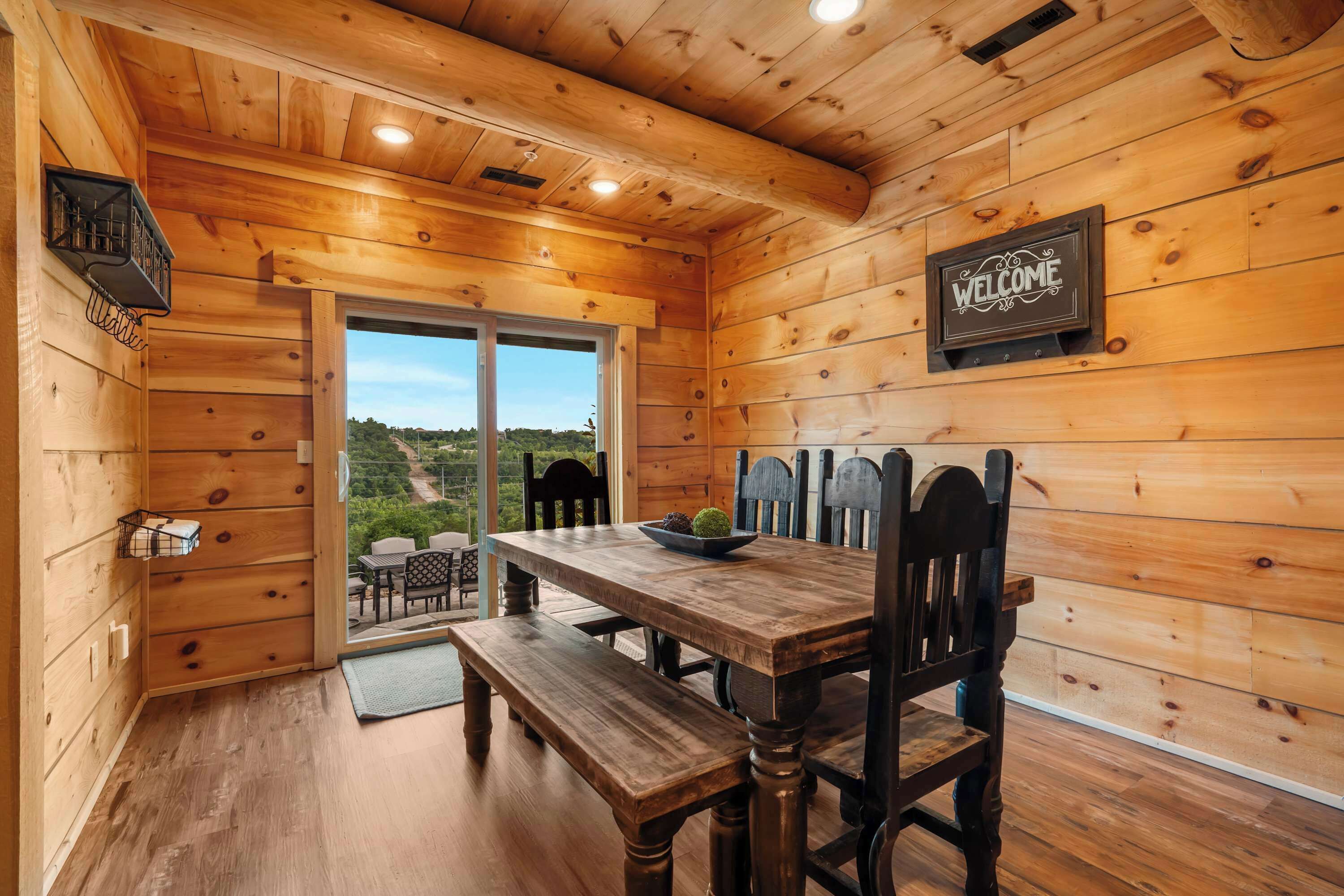 Un intérieur en bois avec une table à manger, des bancs et une pancarte indiquant « BIENVENUE ».