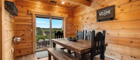 Un intérieur en bois avec une table à manger, des bancs et une pancarte indiquant « BIENVENUE ».