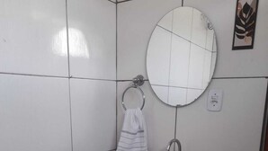 Ein kleines, sauberes Badezimmer mit Toilette, Waschbecken und Spiegel.