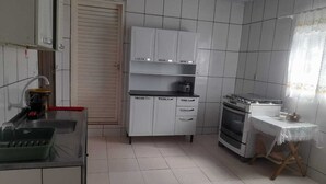 Eine Küche mit weißen Schränken, einem Herd, einem Spülbecken und einem kleinen Tisch mit Tischdecke.