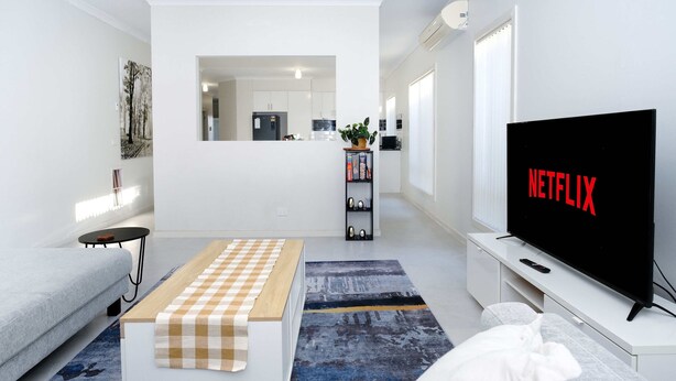 A modern living room with a flat-screen TV displaying "NETFLIX," a sofa, a coffee table, and a bookshelf. - Family And Remote Work Friendly-Only 4 Minutes from The Pacific Werribee (Werribee)