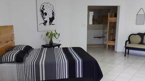 A bedroom with a bed, a bedside table with a plant, a painting on the wall, and a wooden ladder in the background.
