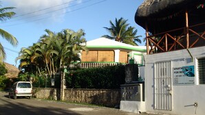 A building with a sign for apartments for rent, a white exterior, and a thatched roof structure.