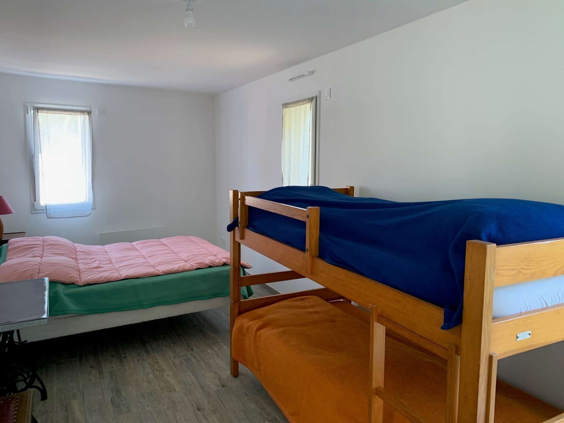 A dormitory room with two bunk beds, a desk, and a chair.