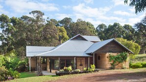 A two-story house with a metal roof, a covered porch, and a garden with various plants.