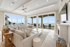 A spacious living room with a large beige sectional sofa, a white coffee table, and a fireplace.