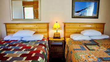 Two double beds with wooden headboards, a nightstand with a lamp, and a mirror on the wall.