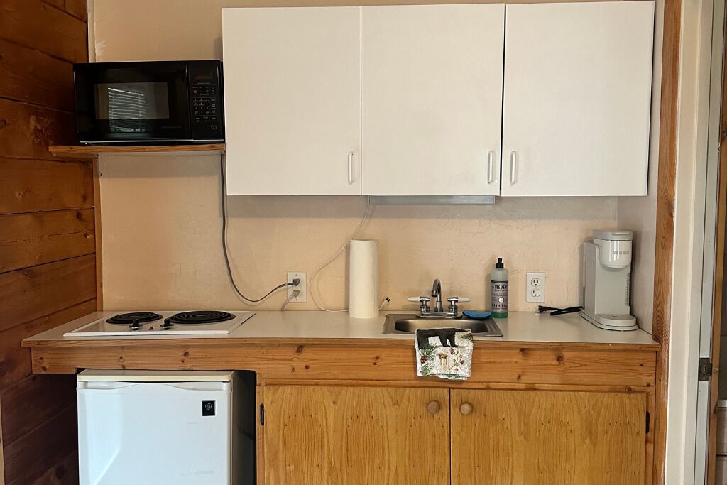 A compact kitchen with a microwave, stove, sink, and a small refrigerator.