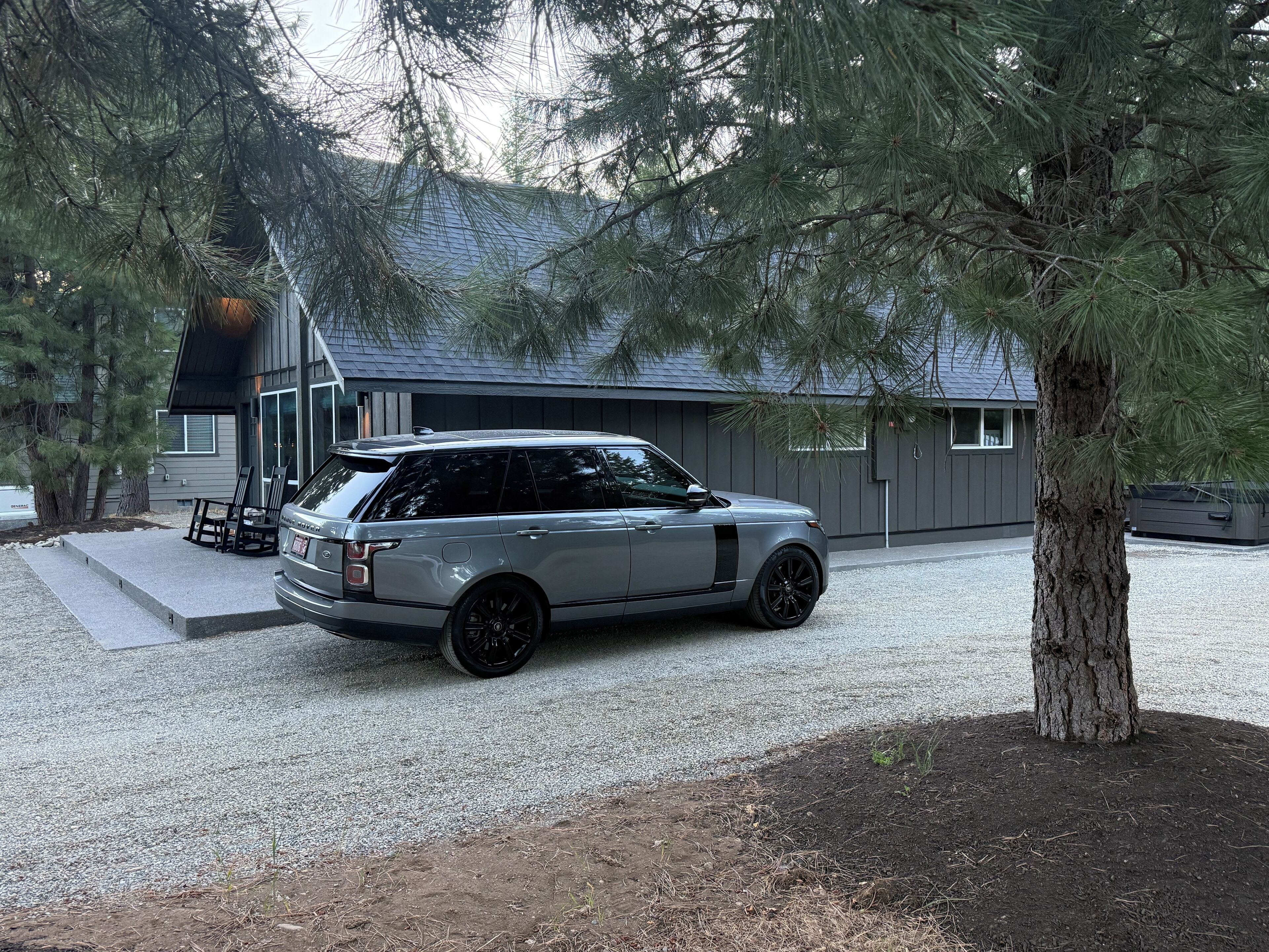 A modern house with a gravel driveway and a parked Range Rover.