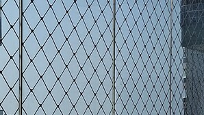 A view through a chain-link fence, featuring a beach and buildings in the background. - 2 bedrooms, 1 suite, 2 bathrooms, balcony with sea view, wifi, hammock, cozy (Cidade Ocian Praia Grande)