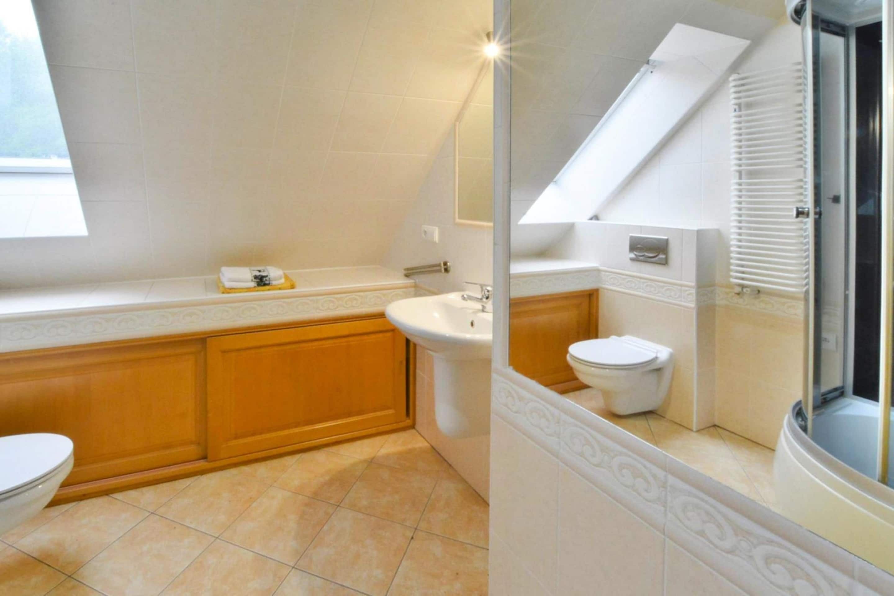 A bathroom with a bathtub, a sink, and a toilet. There is a window providing natural light.
