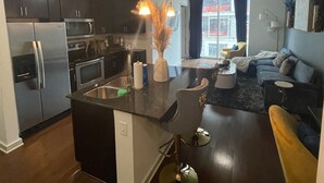 A modern kitchen with dark cabinetry, stainless steel appliances, and a central island. - Royal Escape Midtown High Rise (Atlanta)