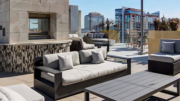 A rooftop patio with a stone wall, outdoor seating, and a fire feature. - Royal Escape Midtown High Rise (Atlanta)