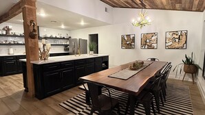 A spacious kitchen with a wooden ceiling, a large island, and black cabinets.