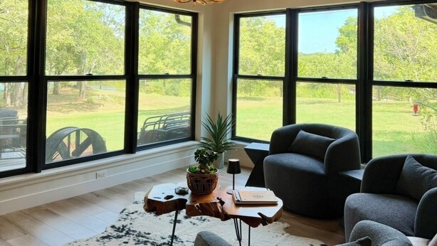 A spacious room with a high ceiling, large windows, and a rustic chandelier.