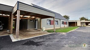 A building with a covered parking area, a garage, and a grassy lawn.