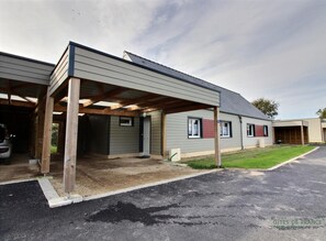 Ein Gebäude mit überdachtem Parkbereich, Garage und Rasenfläche.