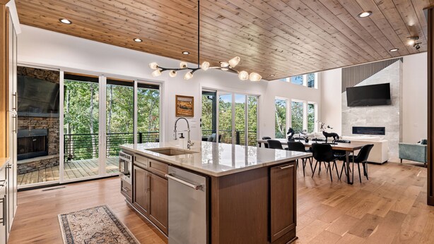 A spacious kitchen with a large island, wooden ceiling, and large windows offering views of greenery. - Modern Mountain Haus - 7 bedroom/5 bath/5 decks/4 fireplaces/Theater - 6195 sqft (Blue Ridge)