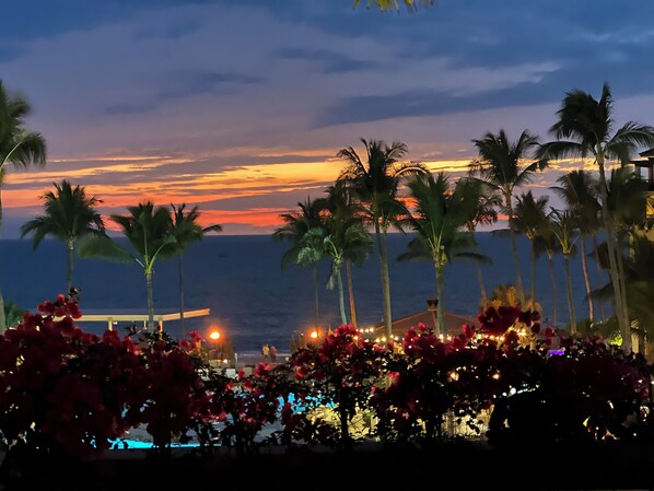 Una vista al atardecer con palmeras y una zona de piscina.