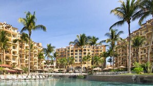 Un resort con edificios de varios pisos, una piscina central y palmeras.