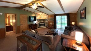 A cozy living room with a stone fireplace, wooden beams, a television, and a comfortable seating area. - Lazy Days @ Spring Brook Resort (Wisconsin Dells)