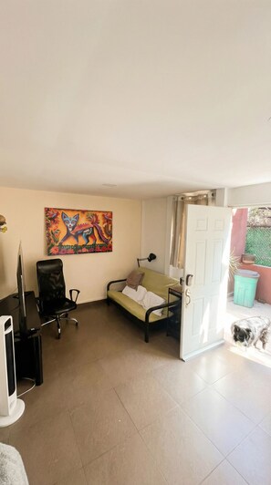 A living room with a sofa, a desk, a chair, and a painting on the wall.