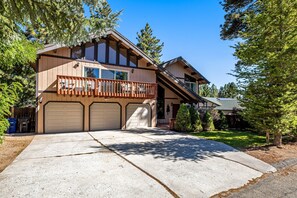 A two-story house with a large garage, a balcony, and a well-maintained lawn.