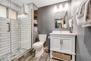 A bathroom with a glass-enclosed shower, a white toilet, and a vanity with a mirror.