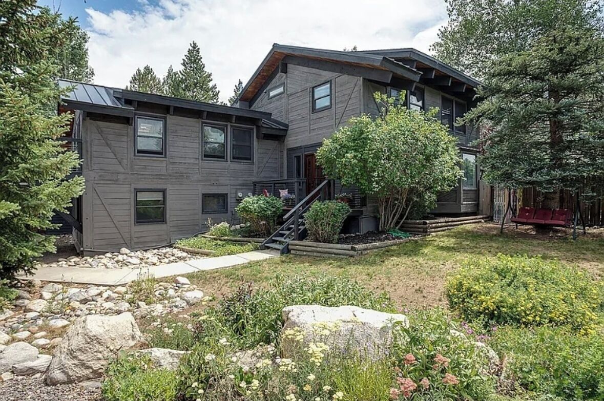 A modern two-story house with a stone pathway leading to the entrance, surrounded by a well-maintained garden and trees.