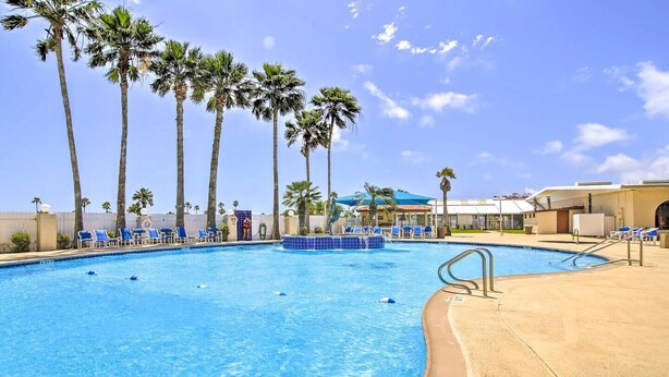 A swimming pool with lounge chairs and palm trees. - Waterfront 2 Bedroom 3 Beds Cottage (Port Isabel)