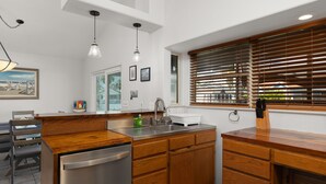 A modern kitchen with wooden cabinets, stainless steel appliances, and a window with blinds. - Waterfront 2 Bedroom 3 Beds Cottage (Port Isabel)