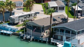 A waterfront property with a dock, a boat, and a house with a balcony. - Waterfront 2 Bedroom 3 Beds Cottage (Port Isabel)