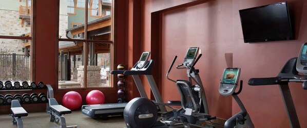 A gym with treadmills, elliptical machines, dumbbells, and exercise balls.