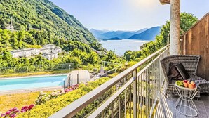A balcony with a view of a lake, a pool, and a mountain range. - Nice apartment for 4 people with WIFI, A/C, pool and terrace (Dizzasco)