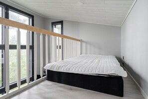 Un dormitorio moderno con cama, ventanas amplias y techo de madera.