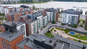 A modern apartment complex with multiple buildings, a marina, and a lake. - Spacious 2BR Apt - Sauna & Lake Views (Jyväskylä)