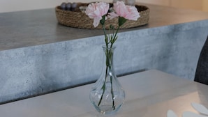 A clear glass vase with pink flowers on a white countertop. - Spacious 2BR Apt - Sauna & Lake Views (Jyväskylä)