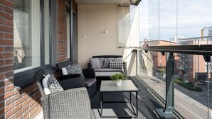 A balcony with wicker furniture, a small table, and a potted plant. - Spacious 2BR Apt - Sauna & Lake Views (Jyväskylä)