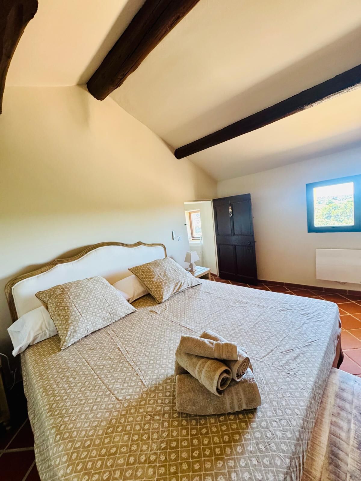 Une chambre à coucher avec un lit, des oreillers, une table de chevet, une armoire et une fenêtre.