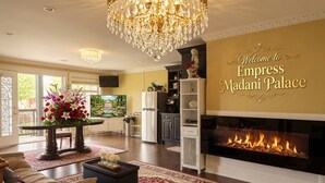 Een ruime woonkamer met een open haard, een kroonluchter en een welkomstbord voor Empress Madani Palace.
