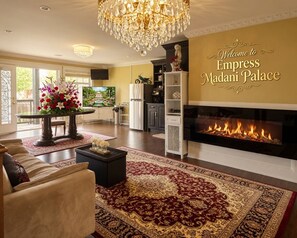 Een ruime woonkamer met een open haard, een kroonluchter en een welkomstbord voor Empress Madani Palace.