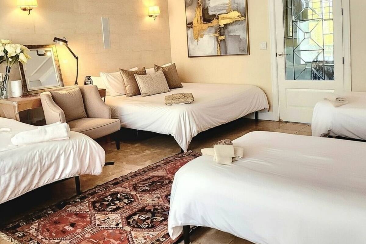 Een hotelkamer met twee bedden, een bank, een kroonluchter en een groot abstract schilderij aan de muur.