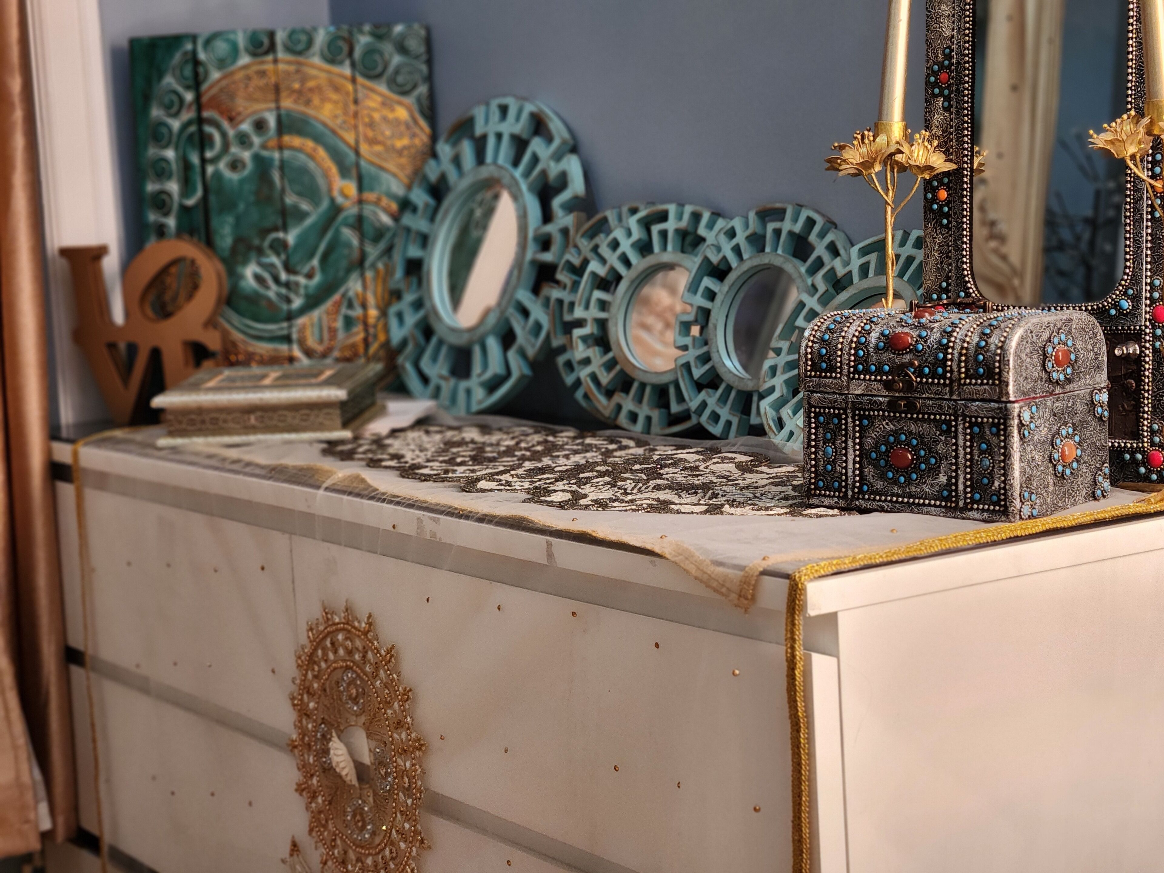 A decorative display with various items including a mirror, a patterned box, and a decorative wall piece.