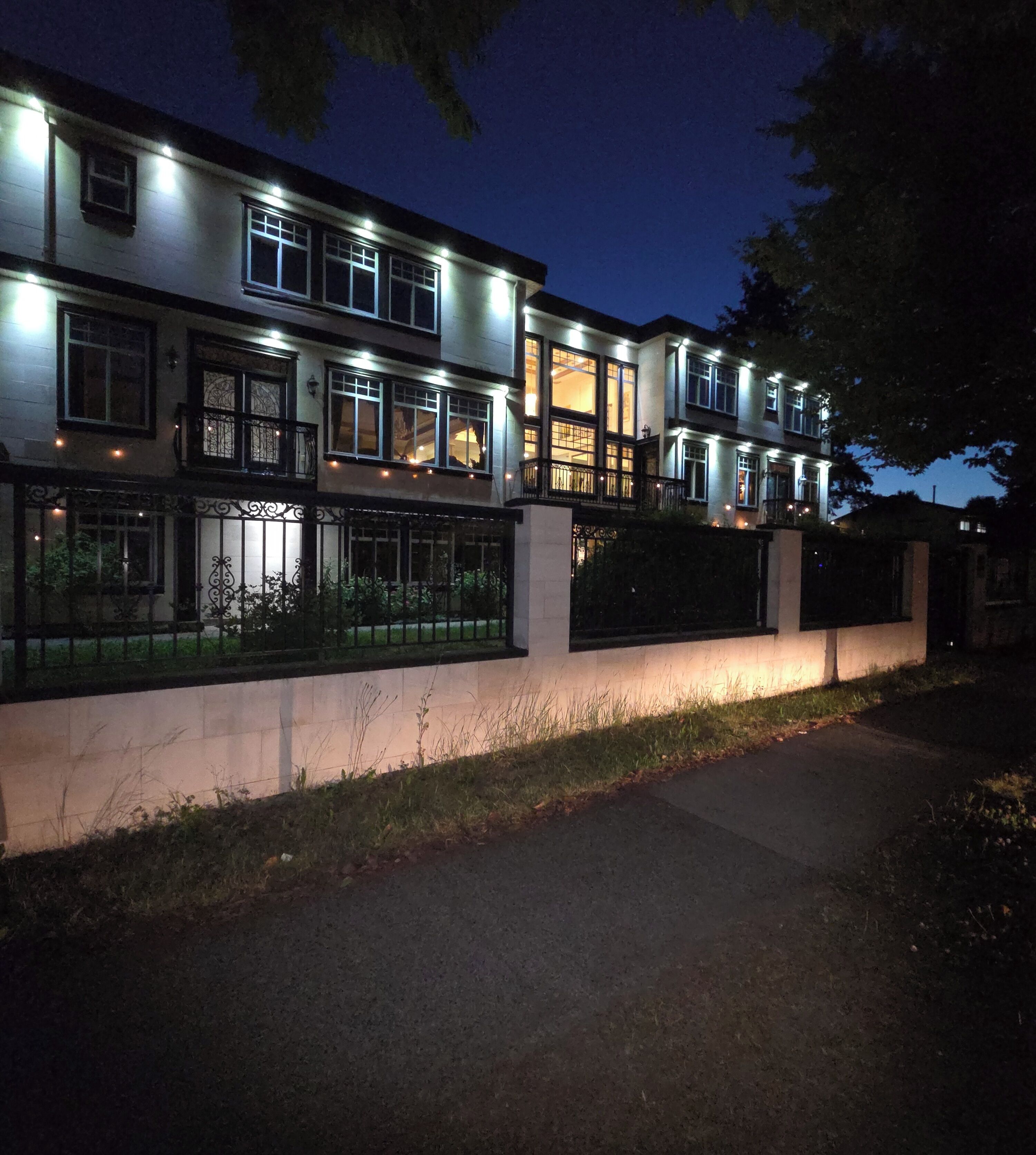A multi-story residential building with illuminated windows and a gated entrance.