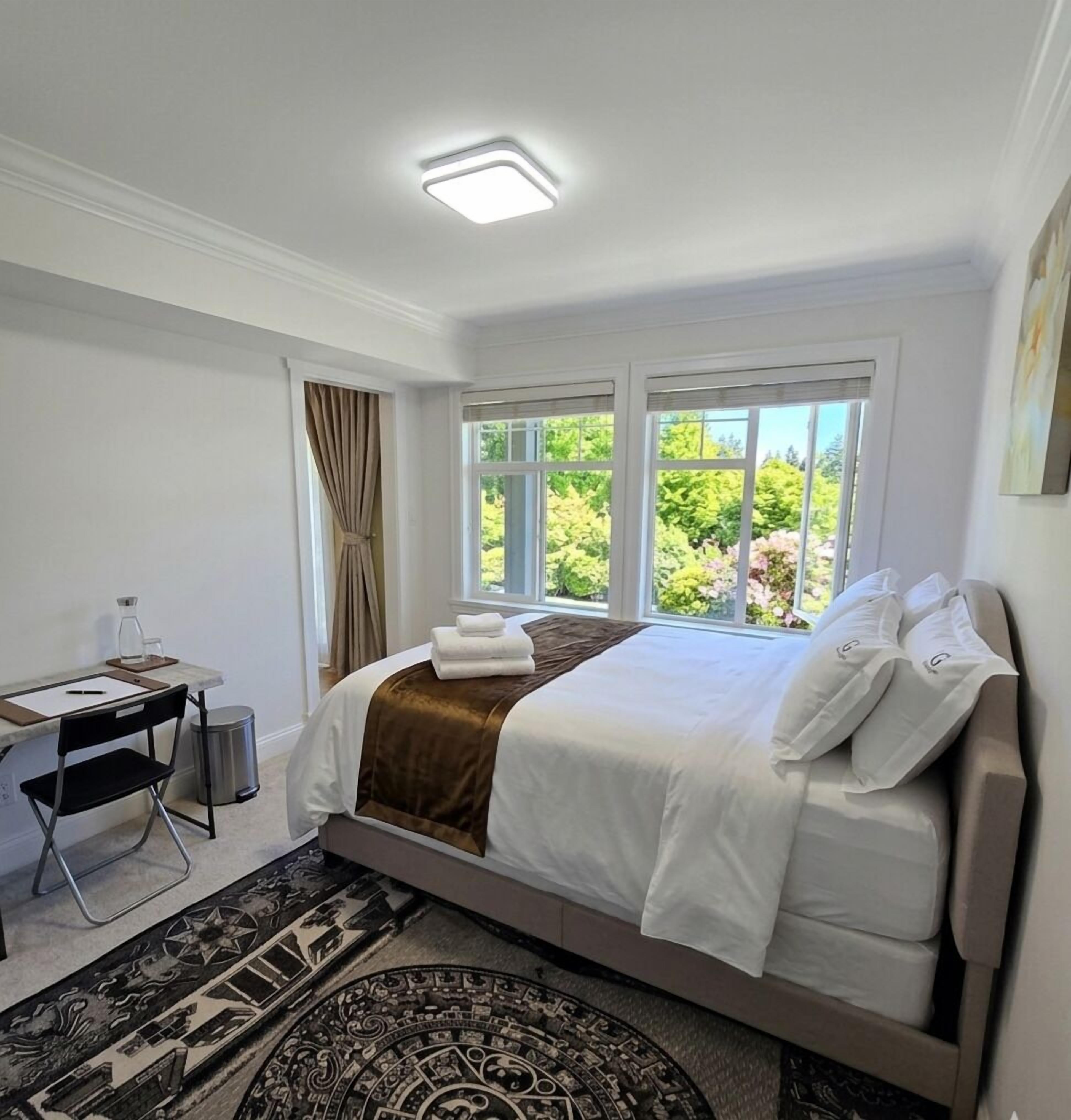 Habitación de hotel con cama, escritorio y ventanas que dan a zonas verdes.