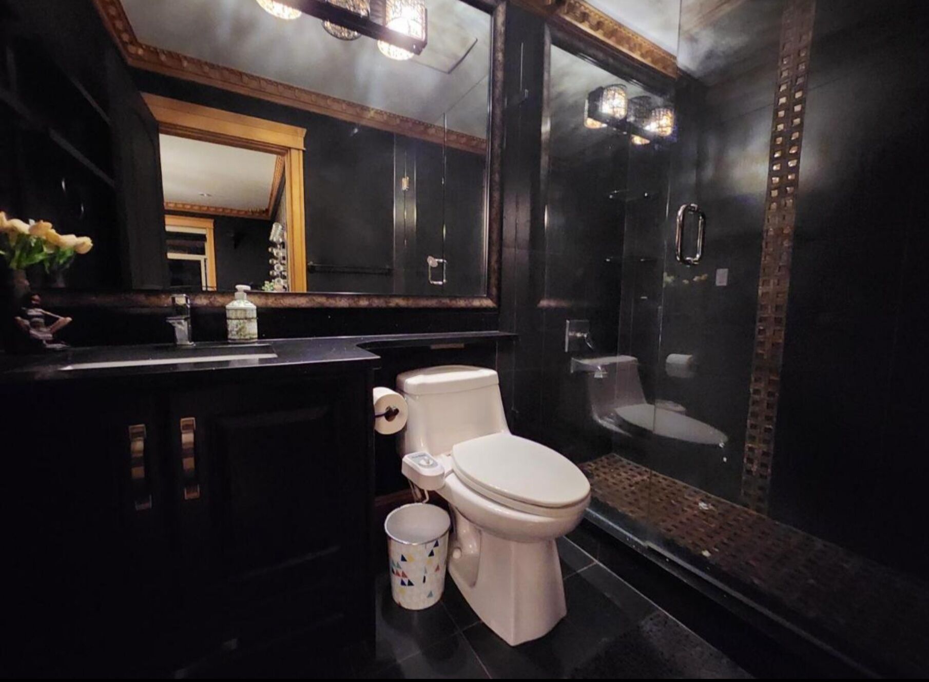 A modern bathroom with a black vanity, a toilet, and a shower.