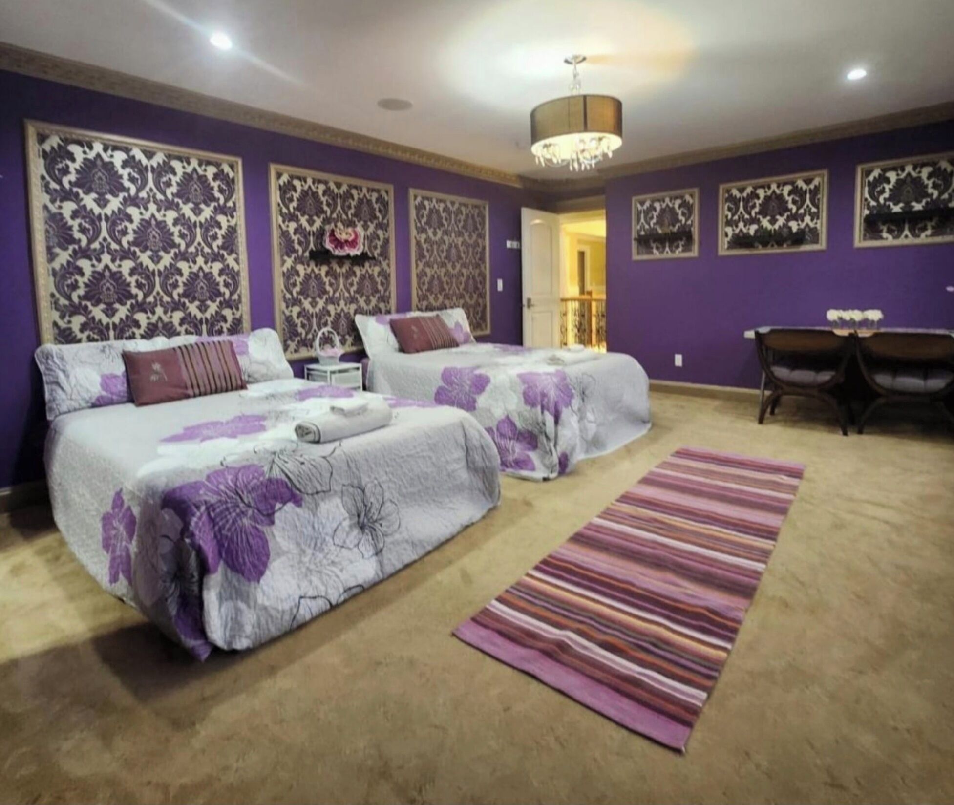 A bedroom with two beds, a chandelier, and patterned wall decorations.