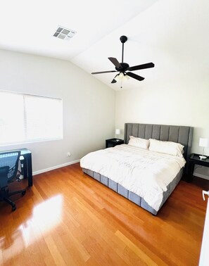 A bedroom with a bed, a desk, a chair, a ceiling fan, and a window. - Phoenix Valley Stay (PHOENIX)