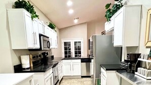 A kitchen with white cabinets, a black countertop, and a tiled floor.