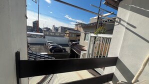 A view from a balcony overlooking a parking area with several cars, a building with a tiled roof, and a clear blue sky. - 8 minutes walk to Sanjo station/12mins walk to GION (京都市左京区聖護院蓮華蔵町)
